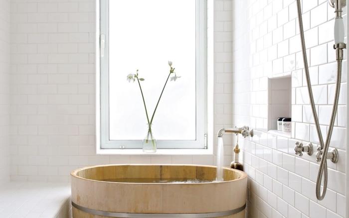 badrumsmodell utrustad i minimalistisk anda, liten badrumsinredning med vita tegelväggar och japanskt badkar i trä