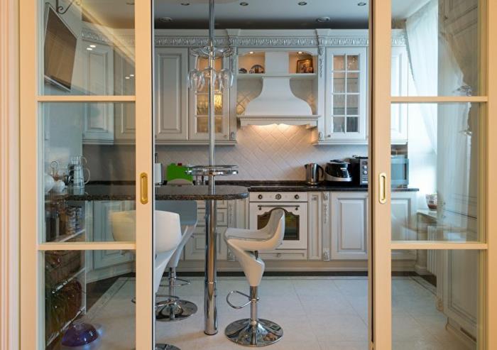 biela kuchyňa oddelená od interiéru posuvnými sklenenými dverami, interiér vo vidieckom štýle v bielej farbe