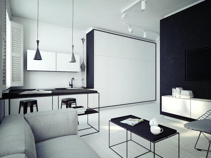 Ako zariadiť bielu a čiernu kuchyňu, kovový bar a stoličky, obývaciu izbu so sivou sedačkou a čierny minimalistický konferenčný stolík