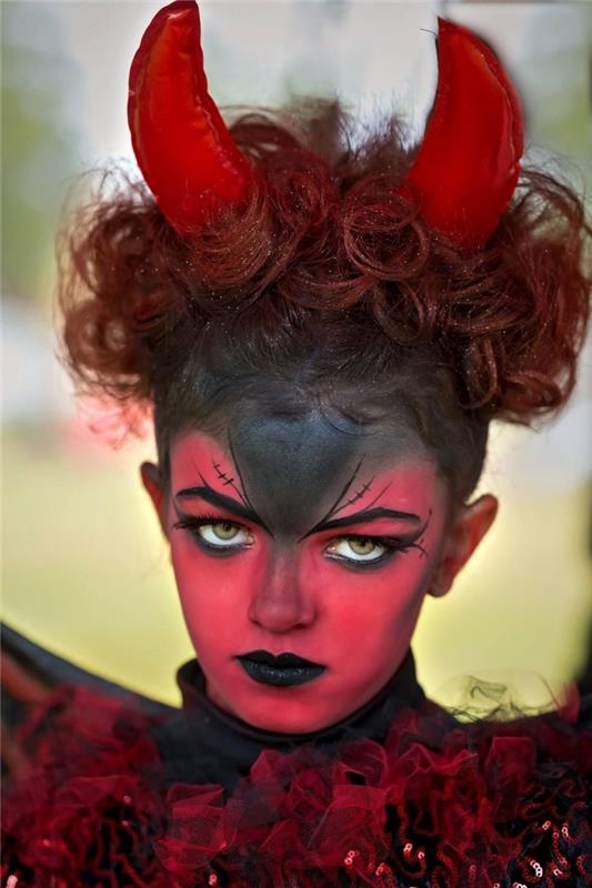 idé för en original tjej halloween kostym, smink liten djävul med hud målad i rött och svart med ögon ögonbryn i djävulshorn, svart mun och ögon understrukna i svart