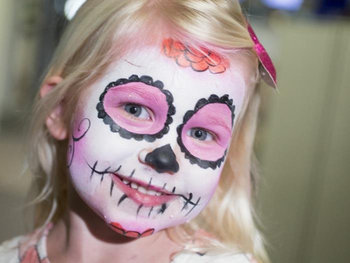 mexický halloween make -up, malá blondínka s ružovým a čiernym make -upom kostry