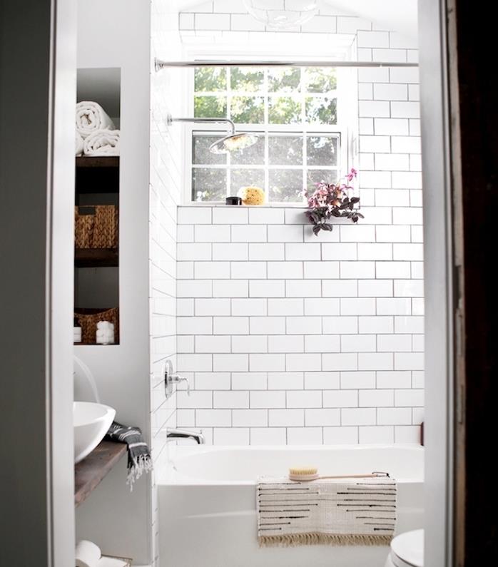 malá kúpeľňa s bielou vaňou, bielym obkladom metra, nástenným výklenkom s úložným priestorom, umývadlom na rustikálnej drevenej doske