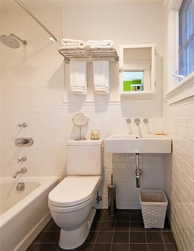 malá kúpeľňa v dĺžke s antracitovou sivou dláždenou podlahou, bielou obkladanou stenou, bielou vaňou na doske, WC a bielym umývadlom