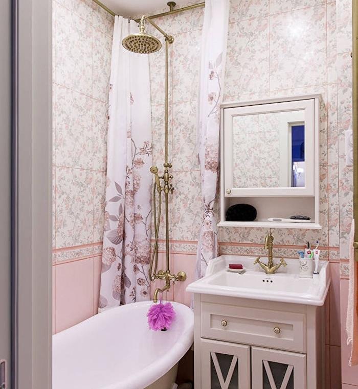 ošumelé elegantné usporiadanie kúpeľne s obkladom s kvetinovou a ružovou potlačou, voľne stojaca vaňa, zlatá sprcha, vysoká skrinka so zrkadlom, biela toaletná jednotka