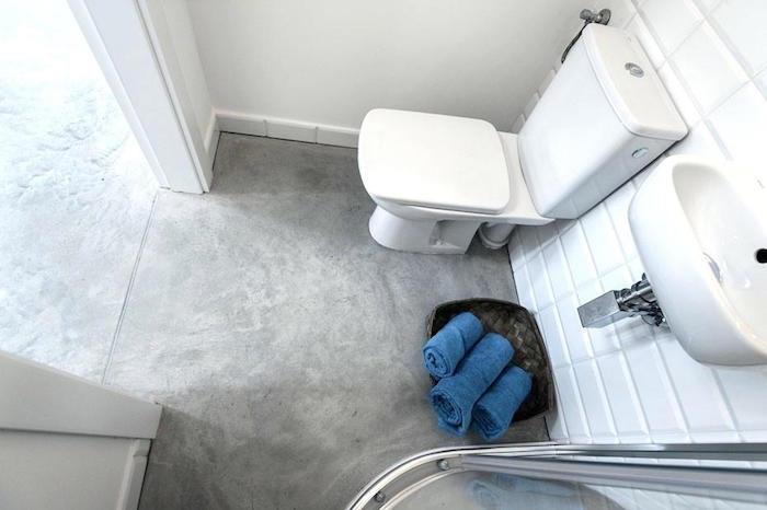 حمام صغير مع دش ومرحاض وأرضية خرسانية مشمع باللون الرمادي