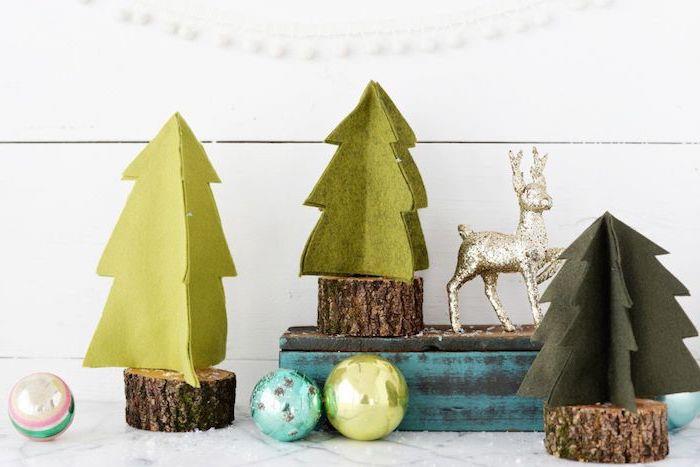 malé drevené polená s mini stromčekmi zo zelenej plsti, ozdoba na vianoce, snehové gule a soby rudolfa v zlate