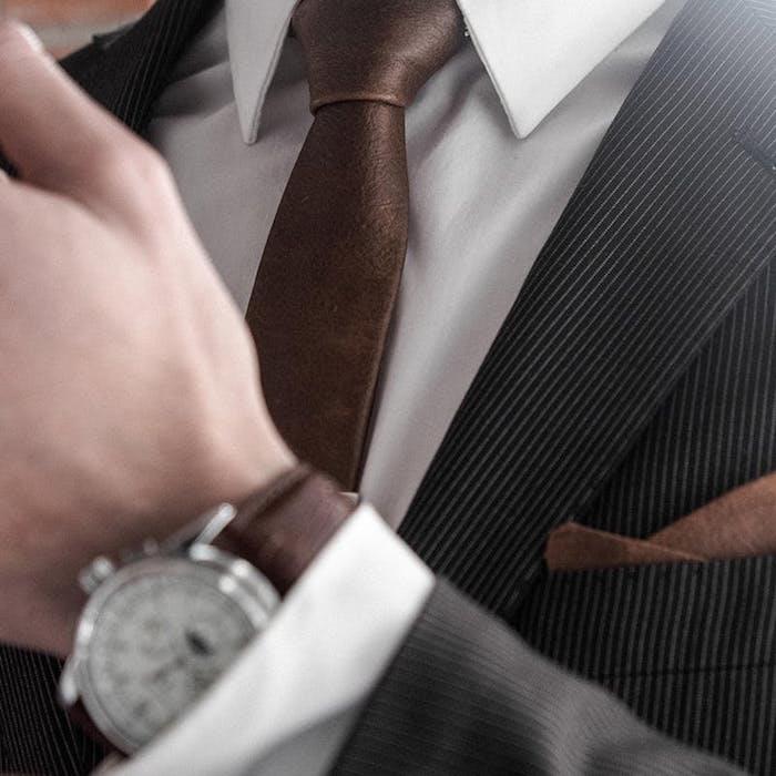 foto av matchande brunt läderband med klocka och ficka på svartgrå randig smoking och vit skjorta