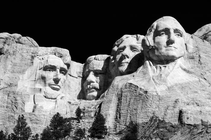 svartvitt bild av berget rushmore med sina fyra presidenter huggen i berget, silhuett mot den svarta bakgrunden av himlen