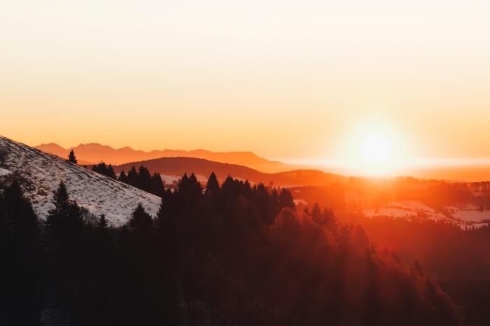 HD tapeta s fotografiou západu slnka nad vzdialenými horami, zasneženým horským kopcom