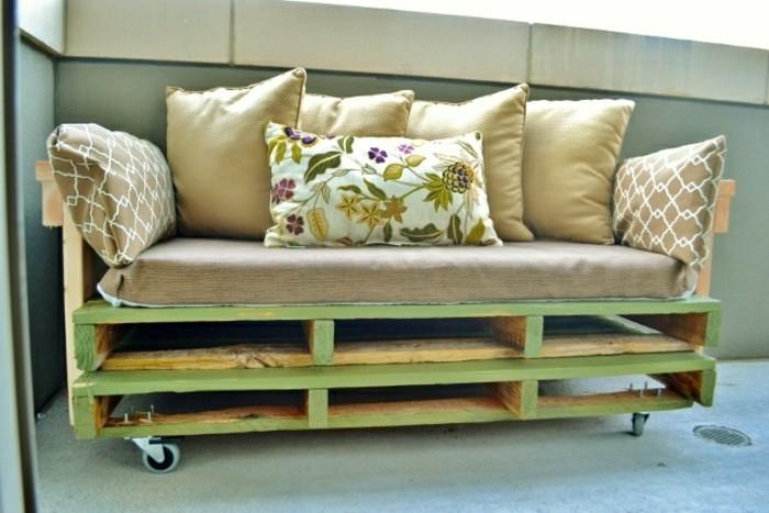 Arredamento con un divano in palet, morbida cuscineria, bancale di legno dipinto di verde