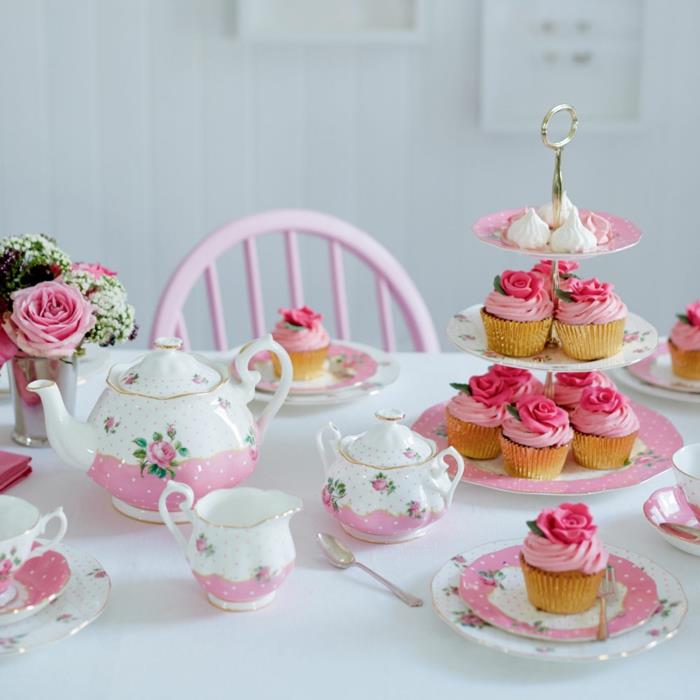 pekná torta z malých koláčov, pomôcky ružovo -biele, malá kytica ruží, biely stôl, ružová stolička