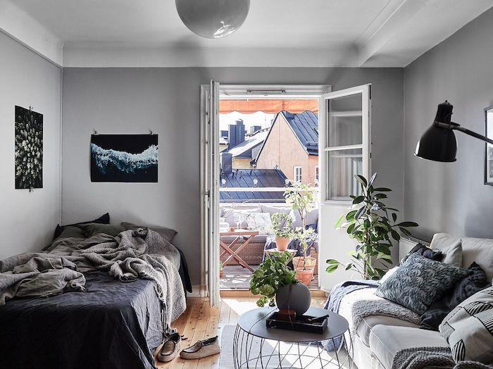 vardagsrum och sovrum i grått och vitt, grått sänglinne, pläd, kuddar och soffa i grå nyanser, som öppnar ut mot en kokande balkong