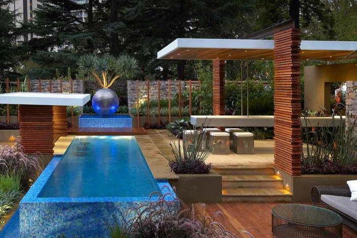 حمام سباحة خارجي بتصميم حديث ، سطح خشبي ، كرة زخرفية كبيرة ، طاولة طويلة ، نباتات معمارية
