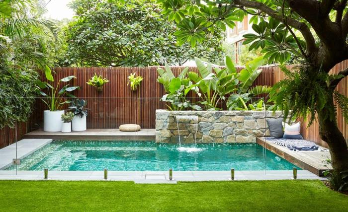 حمام سباحة مع درجات في حديقة ذات مناظر طبيعية جميلة ، قصب الخيزران ، جدار من الحجر الطبيعي ، منطقة استرخاء ، عشب