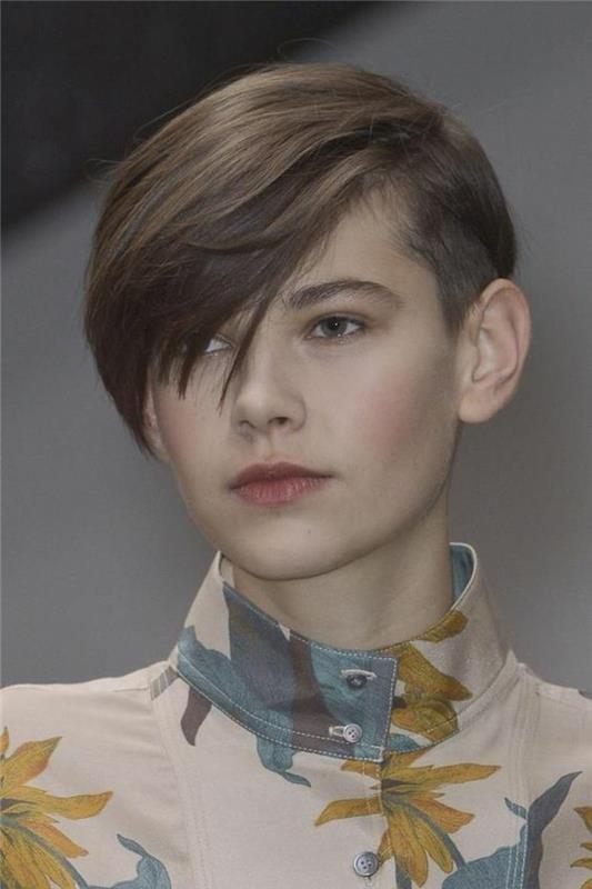 pixie strih, mladá žena s hnedými vlasmi a mužským účesom, bočnými ofinami prepadnutými cez jedno oko, s kvetinovým topom