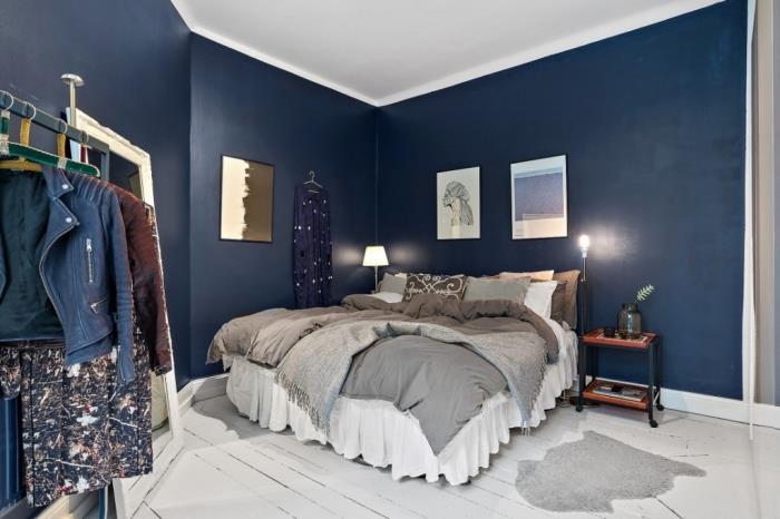 príklad, ako vyzdobiť útulnú spálňu polnočnými modrými stenami s bielym stropom a podlahou, dekoráciou kokonu postele prehozmi a dekoratívnymi vankúšmi