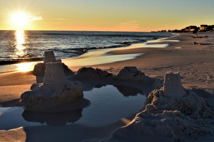 drömlandskap, paradisiskt landskap, strand med sandslott vid solnedgången, mousserande vatten, öde strand, liten oas med slott fyllt med marint vatten