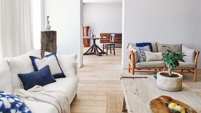 moderná rustikálna výzdoba obývačky s bonsajom na konferenčnom stolíku zo surového dreva, sivobielou pohovkou, bielymi a tmavomodrými vankúšmi, parketami zo surového dreva