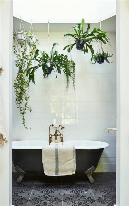 Badrumsinredning i jungelstil med hängande saftig växt, blommiga upphängningar ovanför ett svartvitt badkar