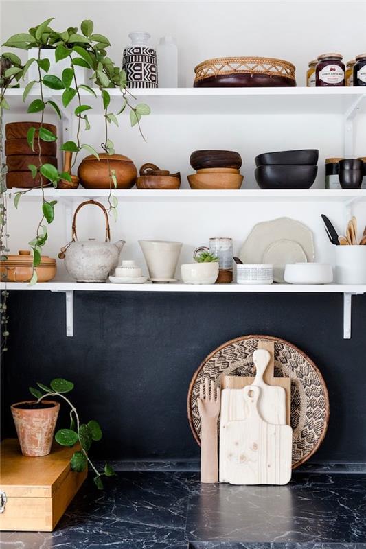 biele otvorené police s odhaleným kuchynským riadom, čierna kuchynská doska s čiernym mramorom a čiernym mramorom, africký dekor so závesnou rastlinou vo vnútri