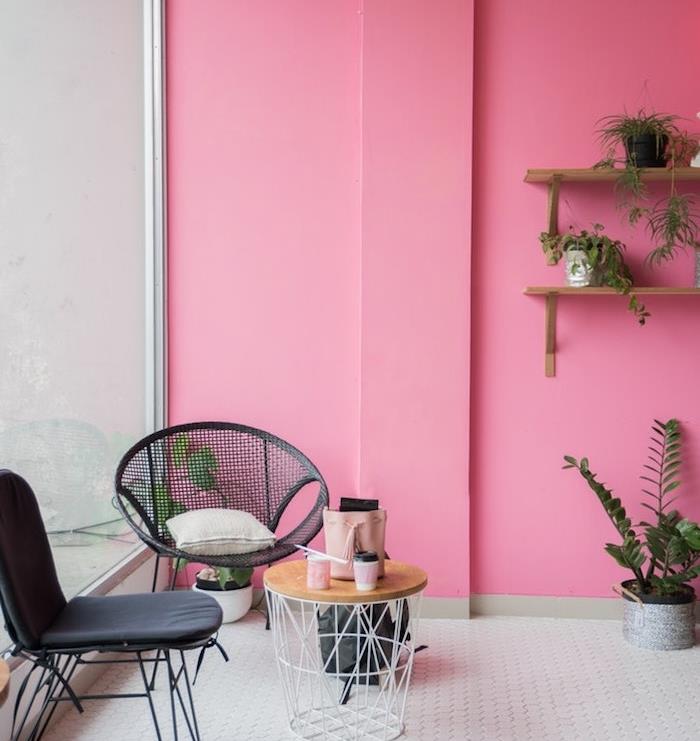 ružové steny, biela dláždená podlaha, čierne stoličky a odpadkový stôl, drevené police zdobené rastlinami v malých zelených kvetináčoch
