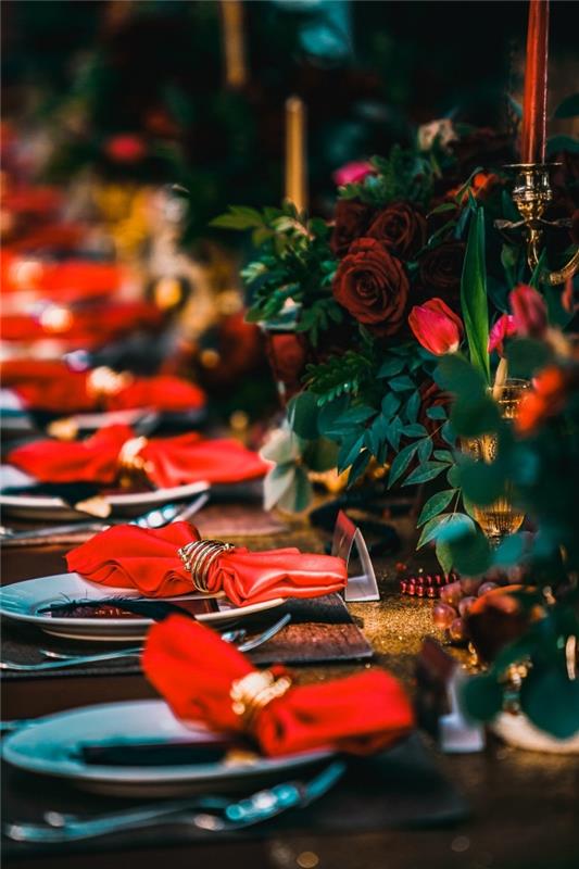 veľkolepá dekorácia vianočného stolu s kyticami červených ruží a zlatých svietnikov, nápad na skladaciu hviezdičku alebo motýľový obrúsok