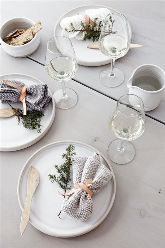 vit servettfällningsidé Juldekor minimalistisk stil vitt träbord vit rund tallrik grankvist