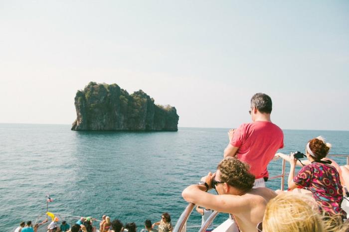paradisiska öar, paradisiskt landskap, holme mitt i havet, blått vatten, turister på en båt som tar bilder