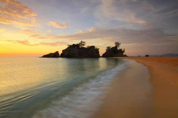 en gudomlig strand, världens vackraste strand, himmel med gula och orange moln, genomskinligt grönt vatten, beige sand, tropiskt skönhetshörna