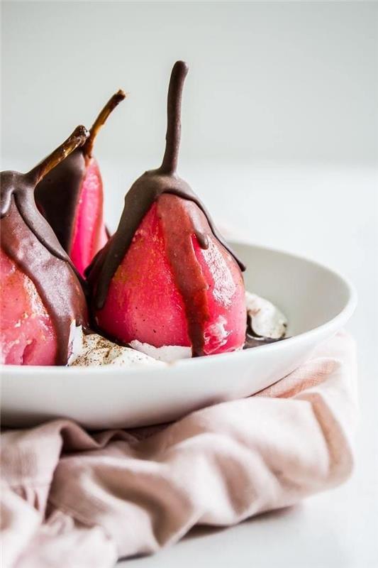 pocherade päron i rött vin insvept i choklad med färsk grädde i en vit tallrik