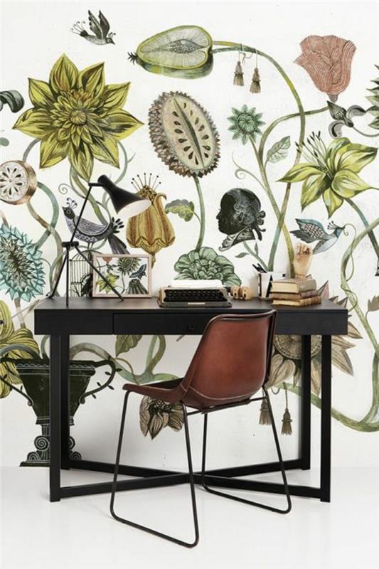 tapet trompe l'oeil med höga växter och örter, i grönt, rött, mörkgrått, hemmakontorets vägg, svart träbord med ben i svart metall, svart metallstol, del av ryggstödet i whiskyfärg, slipat i vitt