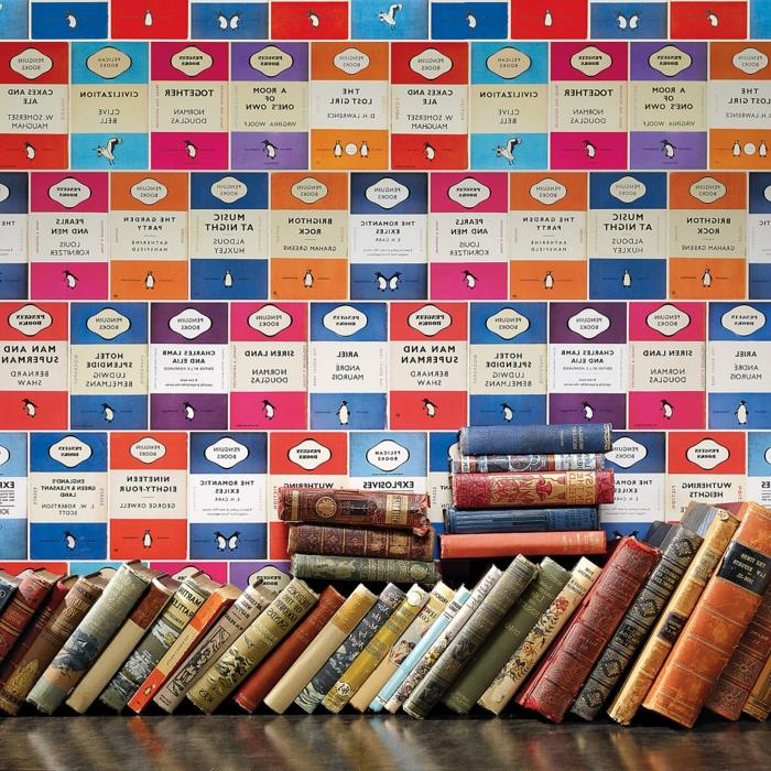 trompe l'oeil tapet med seriemotiv i blått, fuchsia och rött, väggar i ett bibliotek med många böcker, gamla titlar, slitna omslag