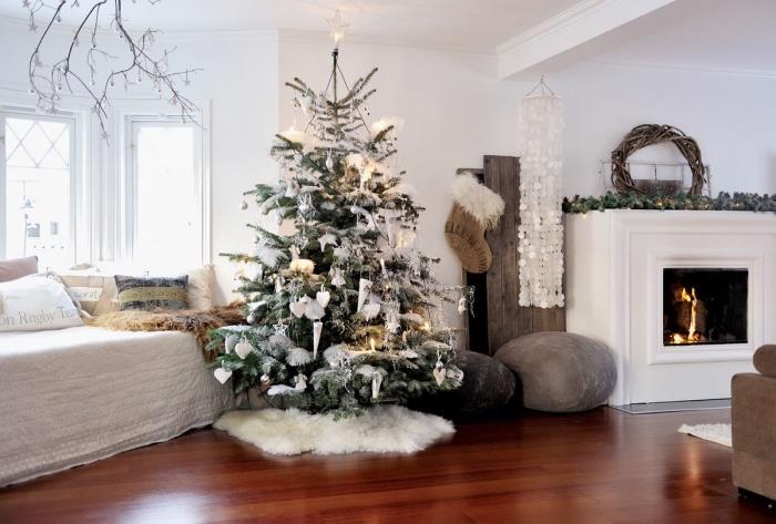 kokongstil inredning i ett vitt vardagsrum med mörka parkettgolv med bruna och grå möbler, julgransdekoration i vitt och grått