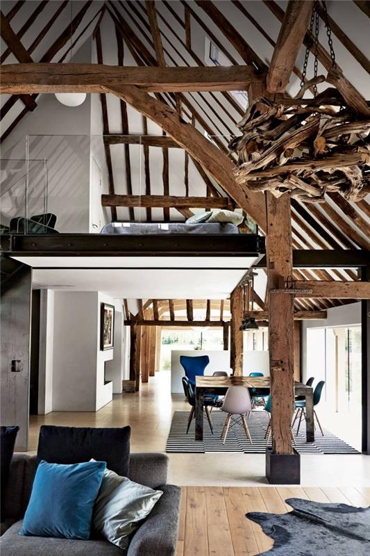 Myšlienka rekonštrukcie stodoly, moderný štýl dekorácie loftového priestoru v bielej a drevenej farbe s matnými čiernymi akcentmi a zamatovými predmetmi