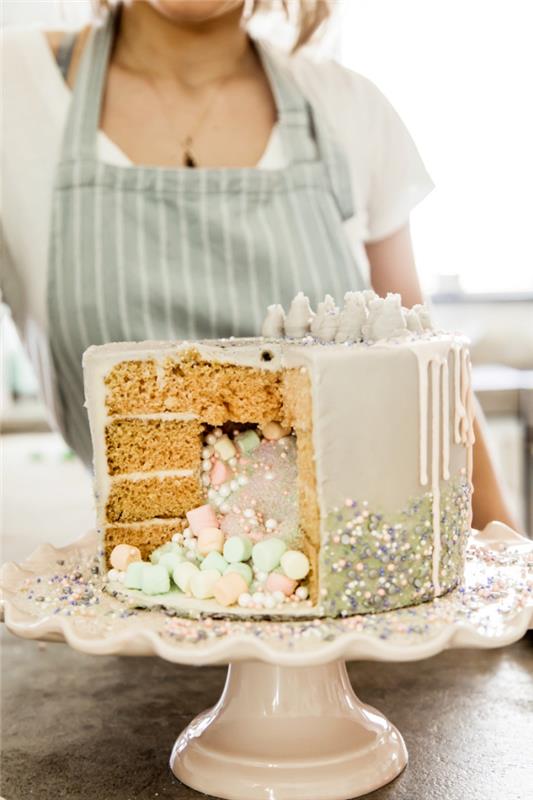 överraskningskaka av vaniljsvampkaka, med flytande glasyr fylld med en blandning av ätbart pulver, sockerpärlor och marshmallows