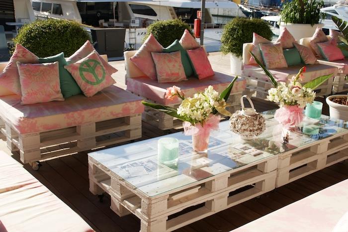 ružový a sivobiely paletový záhradný vankúš na paletových kreslách, konferenčný stolík z paliet so sklenenou doskou, kvetinové kytice deco