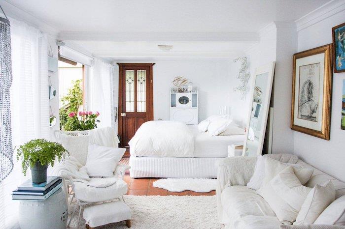 feminin chabby chic deco i vitt med kokosäng och soffa i vitt, blommig deco, stor spegel och vägg av ramar
