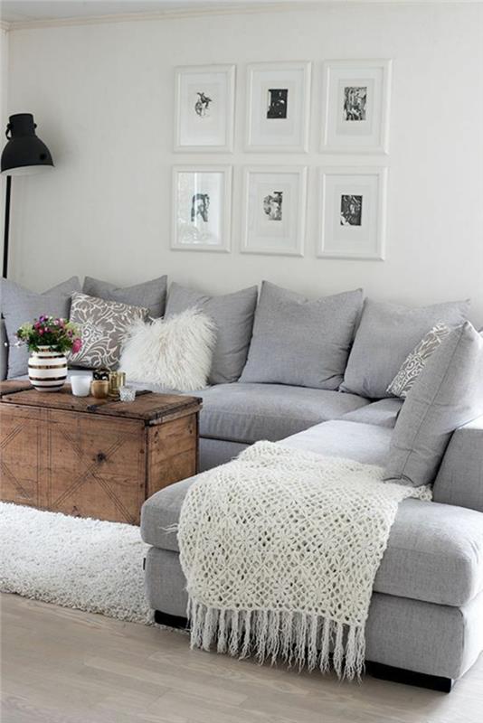 pärlgrå vardagsrum vinkel ljusgrå soffa med stora grå kuddar och sex bord med vita bågar