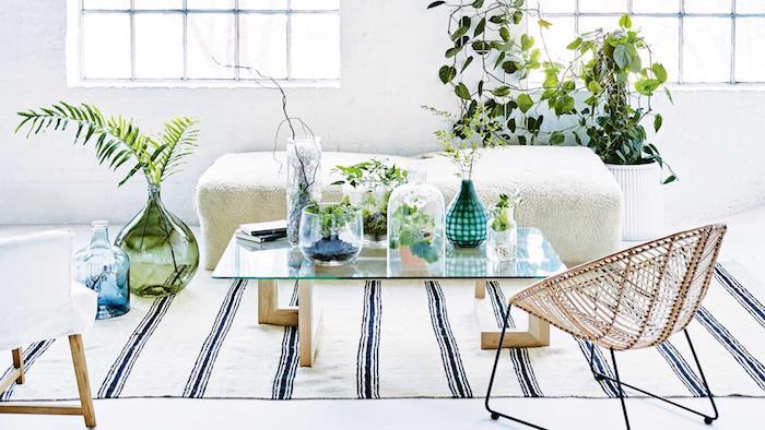 Škandinávska biela a zelená výzdoba obývačky s rastlinami v teráriách pre rastliny, čiernobiely koberec, drevo a sklenený stôl