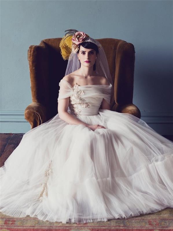 retro elegantný model svadobných šiat pre princeznú s rozprávkovou bielou tylovou sukňou a bielym skladaným topom s odhalenými ramenami, závojom a kvetmi vo vlasoch