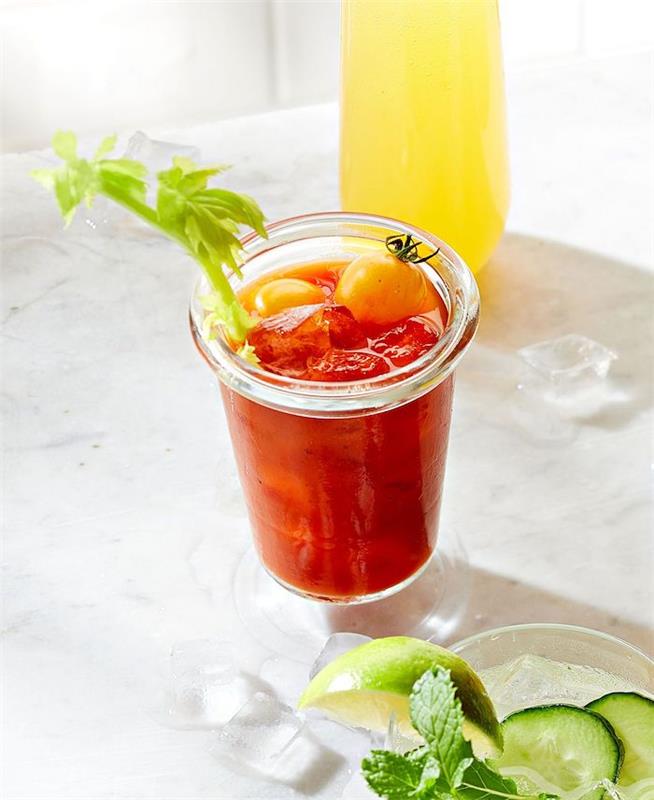 recept na brunch pre krvavú mary kokteil s vodkou a paradajkovou šťavou ozdobený zelerom a olivami vedľa limonády