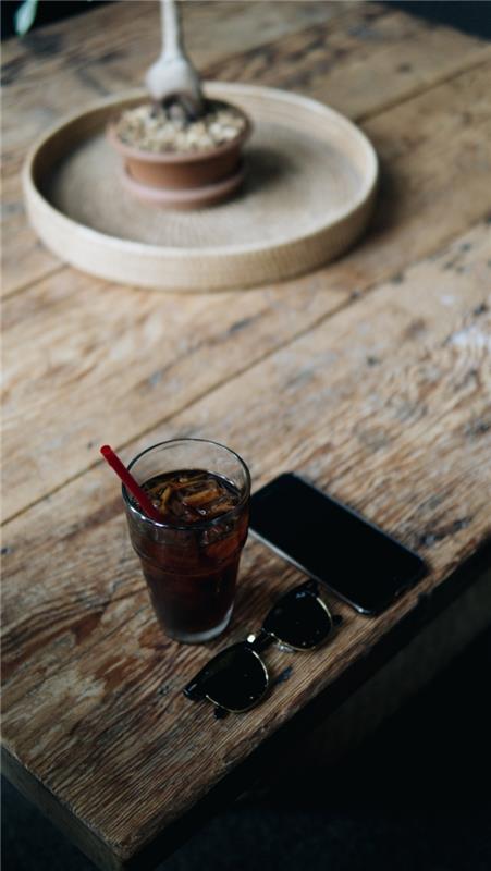 nápad, ako pripraviť originálny nápoj čakanka, pohár naplnený čiernou kávou s kockami ľadu na surovom drevenom stole