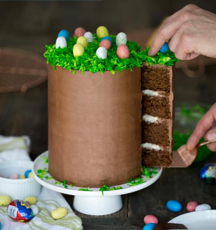 chokladskiktad påsktårta täckt med smörkräm och slät choklad och dekorerad med dekorativt påskgräs