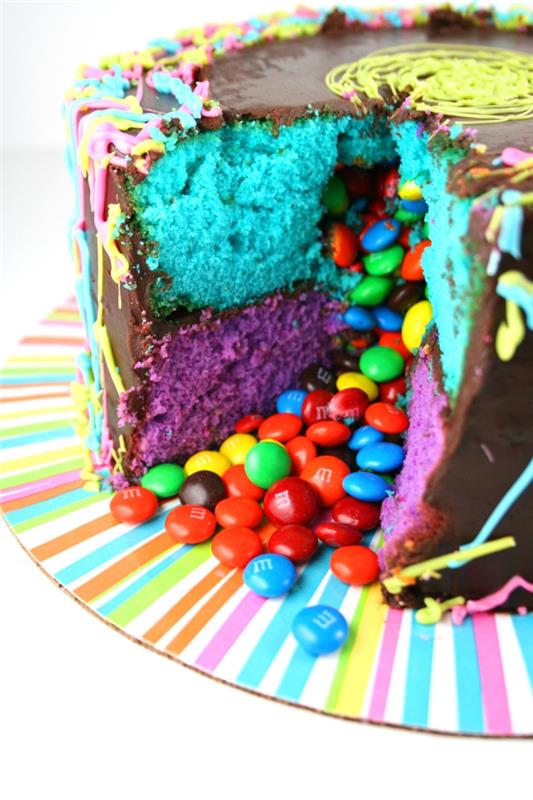 idé för en hemlagad födelsedagstårta, smarties tårta täckt med ganache består av två lager blå och lila sockerkaka som innehåller godis