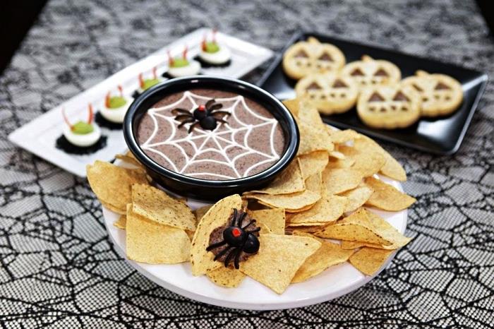enkelt halloweenrecept för att göra svartbönshummus, spindelvävshummus serverad med tortillachips