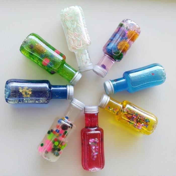 exempel på DIY -sensorflaskor, modellglasflaska fylld med färgat vatten och glitter, DIY -leksaksidé
