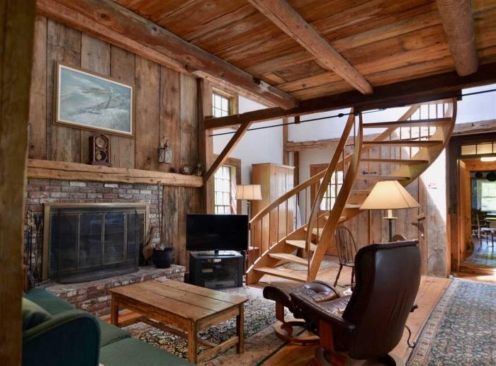príklad stodoly prerobenej na dom, rustikálna dekorácia obývačky s krbom a hnedým koženým a dreveným nábytkom