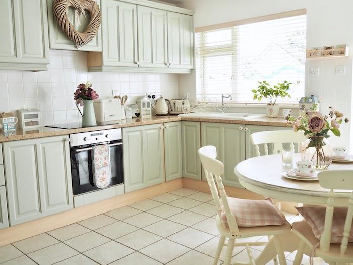 renovera sitt kök, skåp ommålat i ljusgrönt, beige kakel på golvet och vitt på stänkbacken, matplats med runt bord och vintage stolar