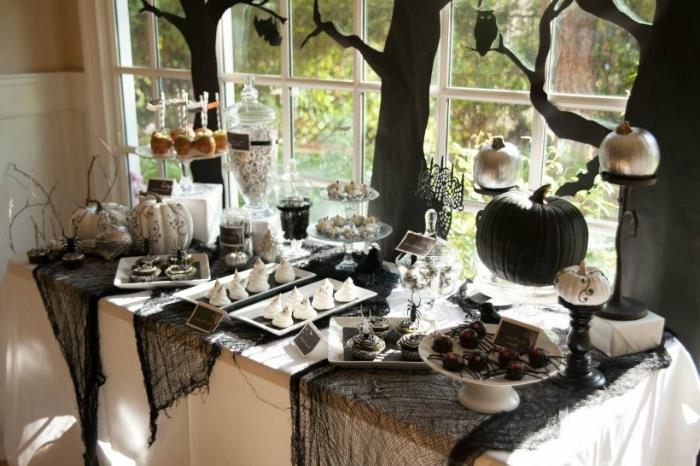 halloween fest med bord täckt med svart spindelnät, desserter och godis med tema Halloween