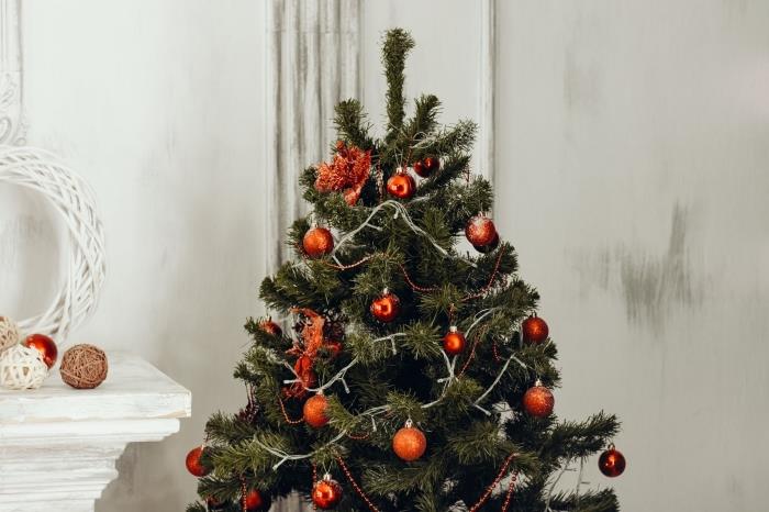 Myšlienka dekorácie vianočného stromčeka s červenými ozdobami a svetlými girlandami, biela dekorácia obývačky na Vianoce s umelým vianočným stromčekom